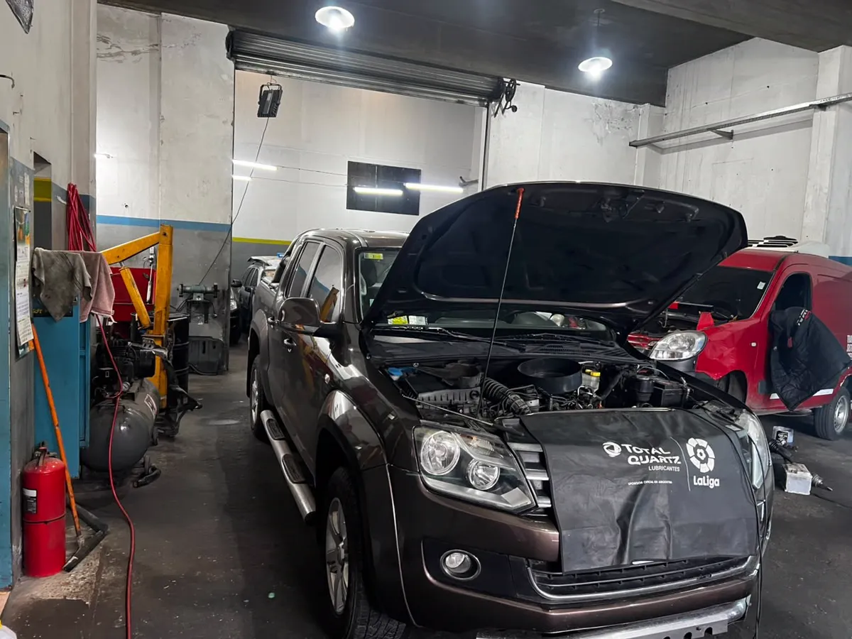Vista general del taller con vehículo en reparación y puertas abiertas